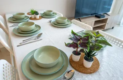 a white table with plates and plants on it at Homes Beyond l Spacious 2BR Creekside Lifestyle in Dubai