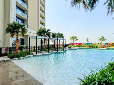 a swimming pool in front of a building with palm trees at High-Floor 2BR in Aykon City Spacious, Good View in Dubai