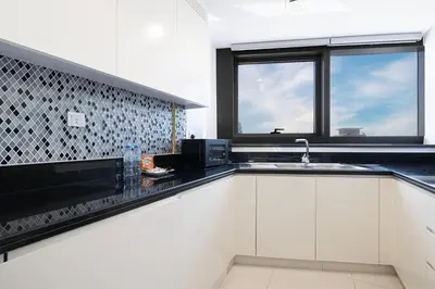 a kitchen with white cabinets and a sink and two windows at SmartStay at Paramount Tower - Sea and Downtown Views - Infinity Pool - Modern Luxury Residences in Dubai