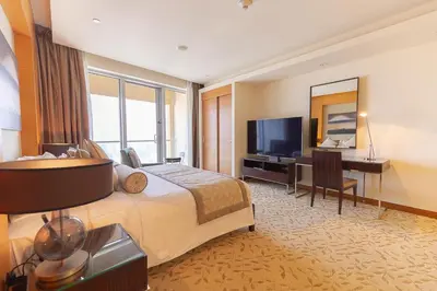 a hotel room with a bed and a desk and a television at Four Apple EMAAR Fashion Avenue Deluxe Studio in Dubai