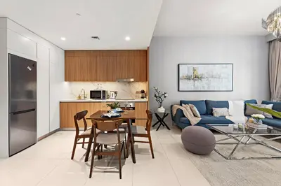 a living room with a blue couch and a table at Stayis I Beachfront Luxury 1BR with Private Access in Dubai