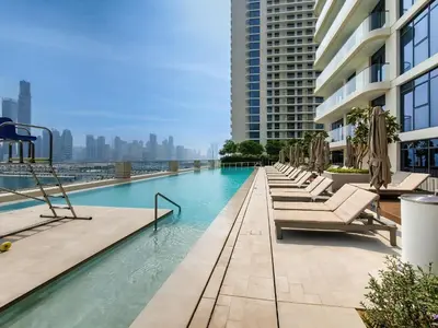 a swimming pool with chaise lounge chairs on a building at Sea and Palm View from 1BD apt in Beachfront in Dubai