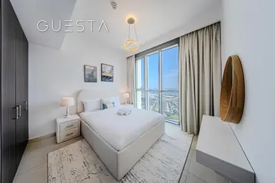 a white bedroom with a bed and a large window at Downtown Views I - Burj Khalifa View, Downtown Dubai in Dubai