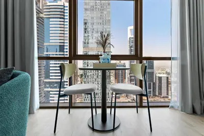 a table and chairs in a room with a large window at Silkhaus Modern Studio in The Heart of DIFC in Dubai