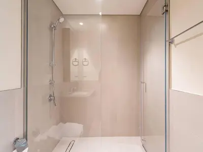 a white bathroom with a shower and a sink at Sunset Creek Oasis: 1BR Gem Luxury Beach Apartment in Dubai