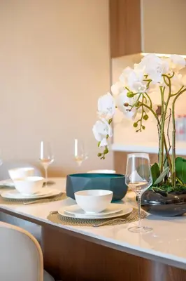 a table with plates and a vase of white flowers at Address Opera Residences Burj Khalifa View in Dubai