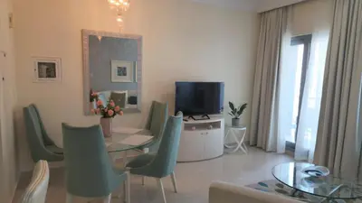 a living room with a table and a television at Damac Maison Mall Street - Downtown by Golden Casa in Dubai