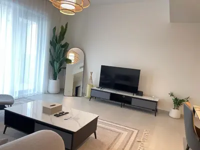 a living room with a television and a table at Pearl of Creek Beach: 1BR Luxury Beach Apartment in Dubai