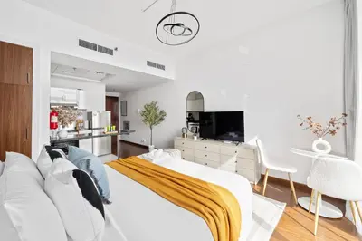 a white bedroom with a bed and a kitchen at Silkhaus Luxury Studio Near Silicon Shopping Mall in Dubai