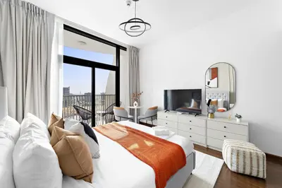 a white bedroom with a large bed and a television at Silkhaus Modern Studio near Silicon Shopping Mall in Dubai