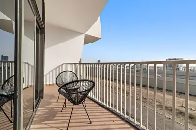 a balcony with two chairs and a view of the beach at Silkhaus Chic Luxury Studio Opposite Silicon Oasis Shopping Mall in Dubai