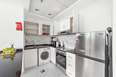 a kitchen with a refrigerator and a washer and dryer at Silkhaus Chic Luxury Studio Opposite Silicon Oasis Shopping Mall in Dubai