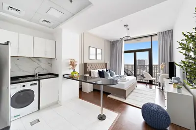 a white kitchen and living room with a couch at Modern Luxurious Studio in Dubai Silicon Oasis in Dubai