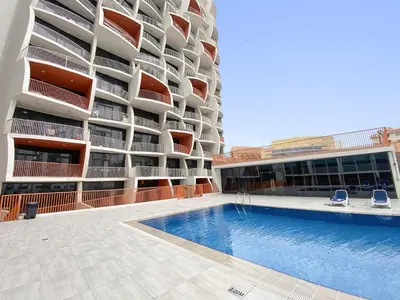 a building with a swimming pool in front of a building at Modern Luxurious Studio in Dubai Silicon Oasis in Dubai