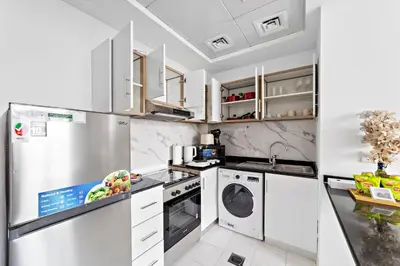 a kitchen with white appliances and white cabinets at Modern Luxurious Studio in Dubai Silicon Oasis in Dubai