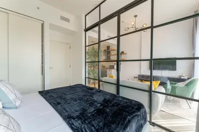 a bedroom with a bed and a glass wall at Cozy One Bedroom Near Dubai Hills Mall in Dubai