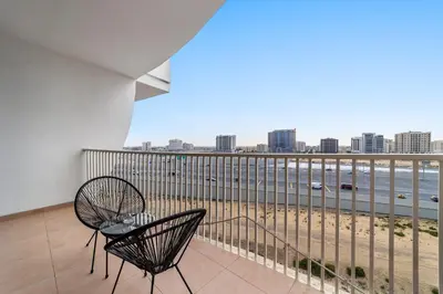 a balcony with two chairs and a view of the beach at Silkhaus Chic Studio Near Silicon Oasis Shopping Mall in Dubai