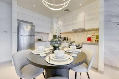 a kitchen with a table and chairs and a refrigerator at Cozy 1BR Haven in The Cove, Dubai Creek Harbour in Dubai