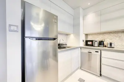 a stainless steel refrigerator in a kitchen with white cabinets at Cozy 1BR Haven in The Cove, Dubai Creek Harbour in Dubai