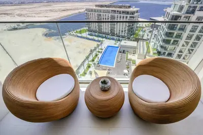 two wooden chairs sitting on a window sill with a view of a city at Cozy 1BR Haven in The Cove, Dubai Creek Harbour in Dubai