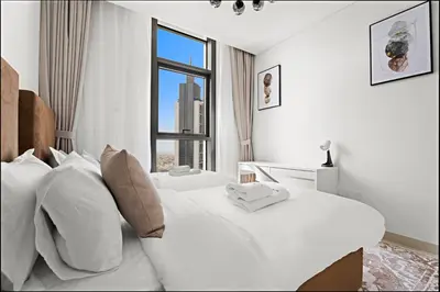 a white bedroom with two beds and a window at Luxurious 2 BR in Downtown Dubai in Dubai