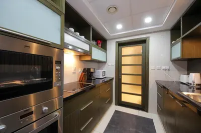 a kitchen with stainless steel appliances and a yellow door at Spectacular 1BHK near Dubai Mall in The Lofts East - TrueBleu Homes in Dubai