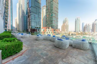 a rooftop patio with blue and white chairs in a city at Cayan Tower Dubai Marina - By Home Of Choice in Dubai