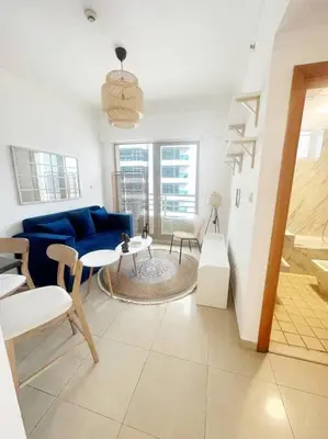 a living room with a blue couch and a table at Lux 1BR w rooftop pool in Marina near metro, Beach in Dubai