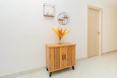 a vase of flowers on a wooden cabinet in a room at Dubai Marina - 1BHK Apartment in Dubai