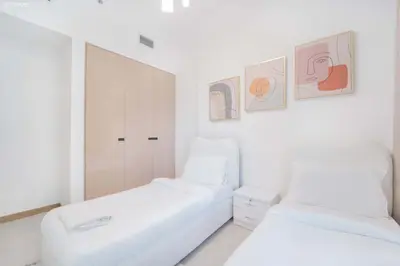 two white beds in a white room with pictures on the wall at Fabulous Missoni Designer Building, 3 bedroom plus maid in Dubai