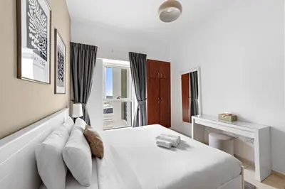 a white bedroom with a bed and a window at Splendid 1BR APT in Dubai Marina in Dubai