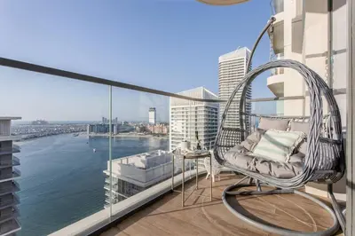 a wicker chair on a balcony with a view of the water at Sky-High 1BR RetreatMarina VistaEmaar Beachfront in Dubai