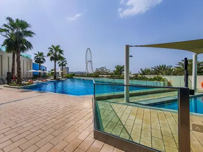 a swimming pool at a resort with palm trees at Address JBR 2 Bedroom With Beach Access by Millennium Vacation Homes in Dubai