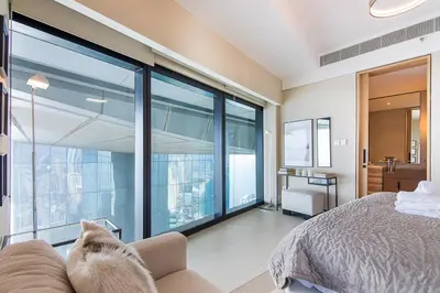 a cat sitting on a couch in a bedroom with a large window at Address JBR 2 Bedroom With Beach Access by Millennium Vacation Homes in Dubai