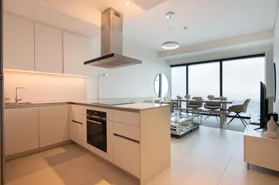 a kitchen with white cabinets and a dining room at Address JBR 2 Bedroom With Beach Access by Millennium Vacation Homes in Dubai