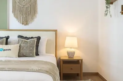 a bedroom with a bed and a table with a lamp at HiGuests - Luxurious Boho Beach 2BR Apartment in La Mer in Dubai