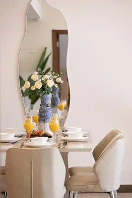 a dining room table with a vase of flowers and a mirror at SmartStay at Zaya Hameni - Modern Luxury Apartments - Unique in JVC in Dubai