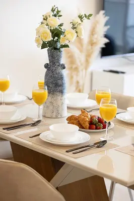 a table with a vase of flowers and orange juice at SmartStay at Zaya Hameni - Modern Luxury Apartments - Unique in JVC in Dubai
