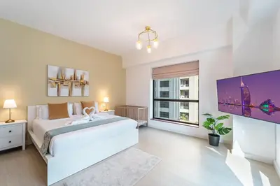 a white bedroom with a large bed and a tv at Prime Spacious 5 plus 1 BR Apt on JBR Beach near Metro ,Walk to The Mall, Dining & Entertainment - By Sunkissed Holiday Homes in Dubai