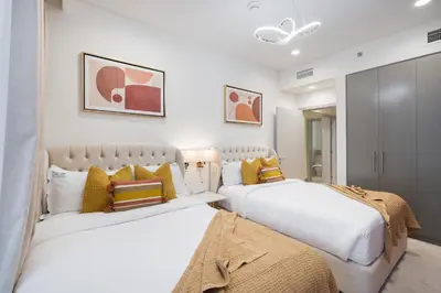 two beds in a bedroom with white walls and yellow pillows at Heaven Crest Vacation Homes - Luxury Forte in Dubai