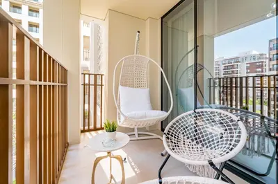 a balcony with a swing chair and a table at SettlerHomes - Marvelous Lagoon Stay With Pool View in Dubai