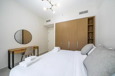 a bedroom with a bed and a desk and a mirror at SettlerHomes - Marvelous Lagoon Stay With Pool View in Dubai