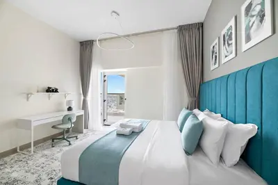 a bedroom with a large bed with a blue wall at Stylish 1 BR in Al Furjan in Dubai