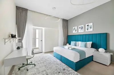 a bedroom with a blue bed and a desk at Stylish 1 BR in Al Furjan in Dubai