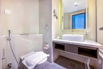 a bathroom with a sink and a toilet and a mirror at Studio Apartment in DAMAC Maison Prive Businessbay - Dubai Canal View in Dubai