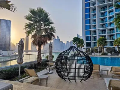 a resort with a pool and palm trees and a building at Studio Apartment in DAMAC Maison Prive Businessbay - Dubai Canal View in Dubai