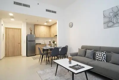 a living room with a couch and a table and a kitchen at Spacious 1 BR in Peaceful Community in Dubai