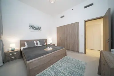 a bedroom with a large bed and a wooden cabinet at Spacious 1 BR in Peaceful Community in Dubai