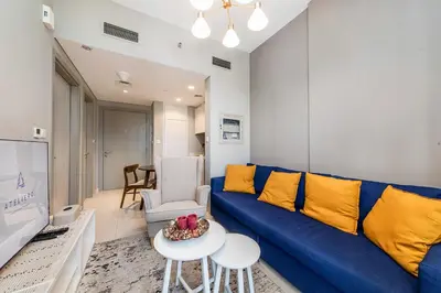 a living room with a blue couch and a tv at Zada Tower 1BR with amazing Dubai Canal view in Dubai