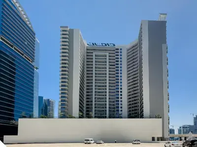 two tall buildings with cars parked in front of them at Zada Tower 1BR with amazing Dubai Canal view in Dubai